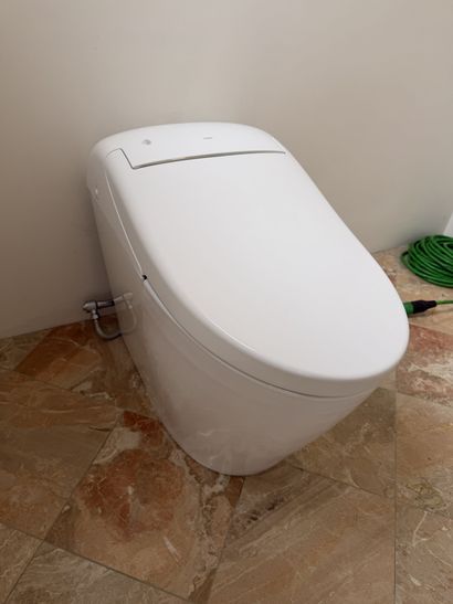 Modern white bidet toilet against a beige wall on a tiled floor