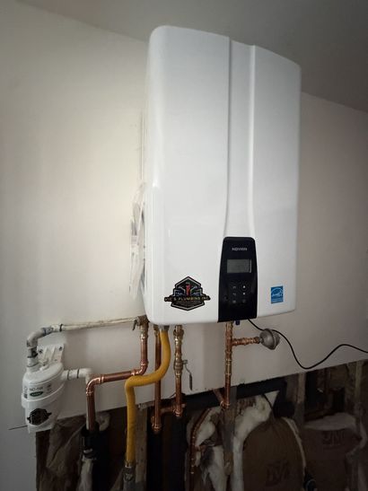White wall-mounted water heater with exposed pipes in a utility room