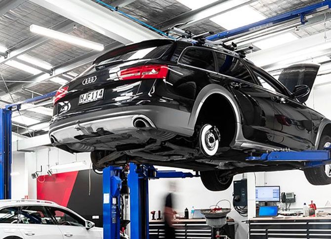 A black audi is sitting on a lift in a garage.