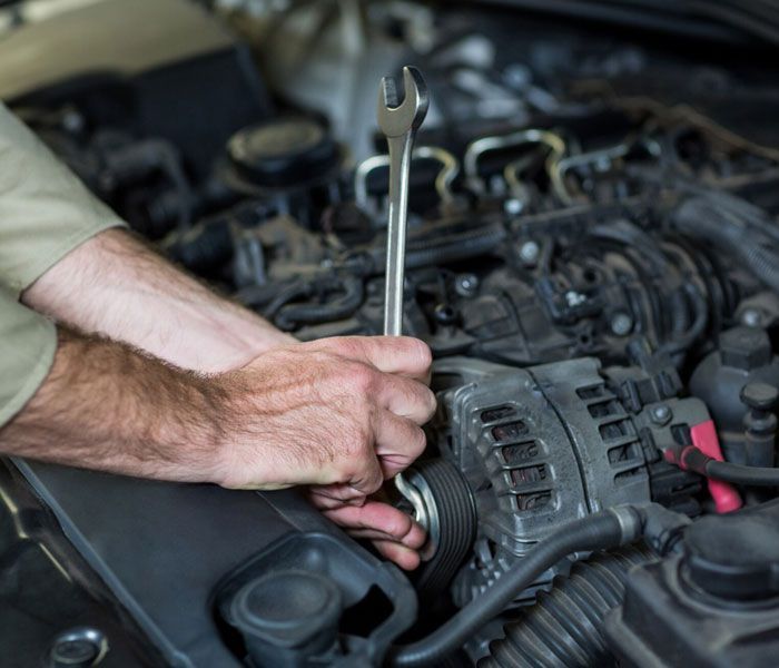 A man is working on a car engine with a wrench