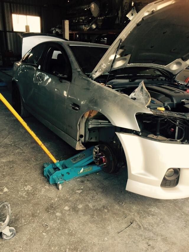 A Car With the Hood Open is Sitting on a Jack in a Garage — Alice Crash Repairs In Ciccone, NT