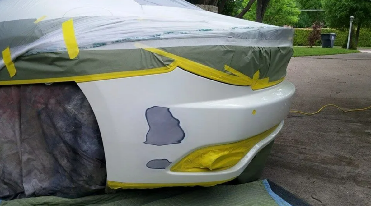 A white car is being painted with yellow tape