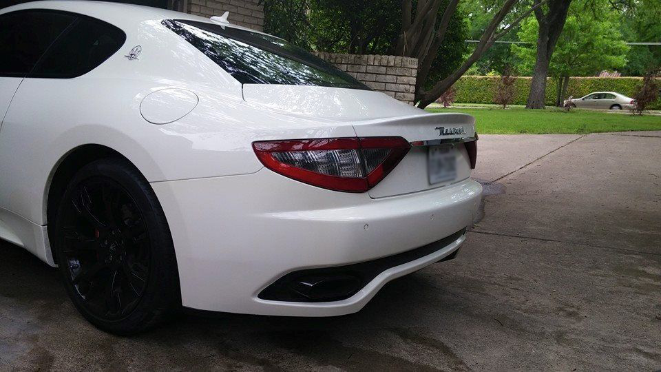 A white car with black wheels is parked in a driveway.