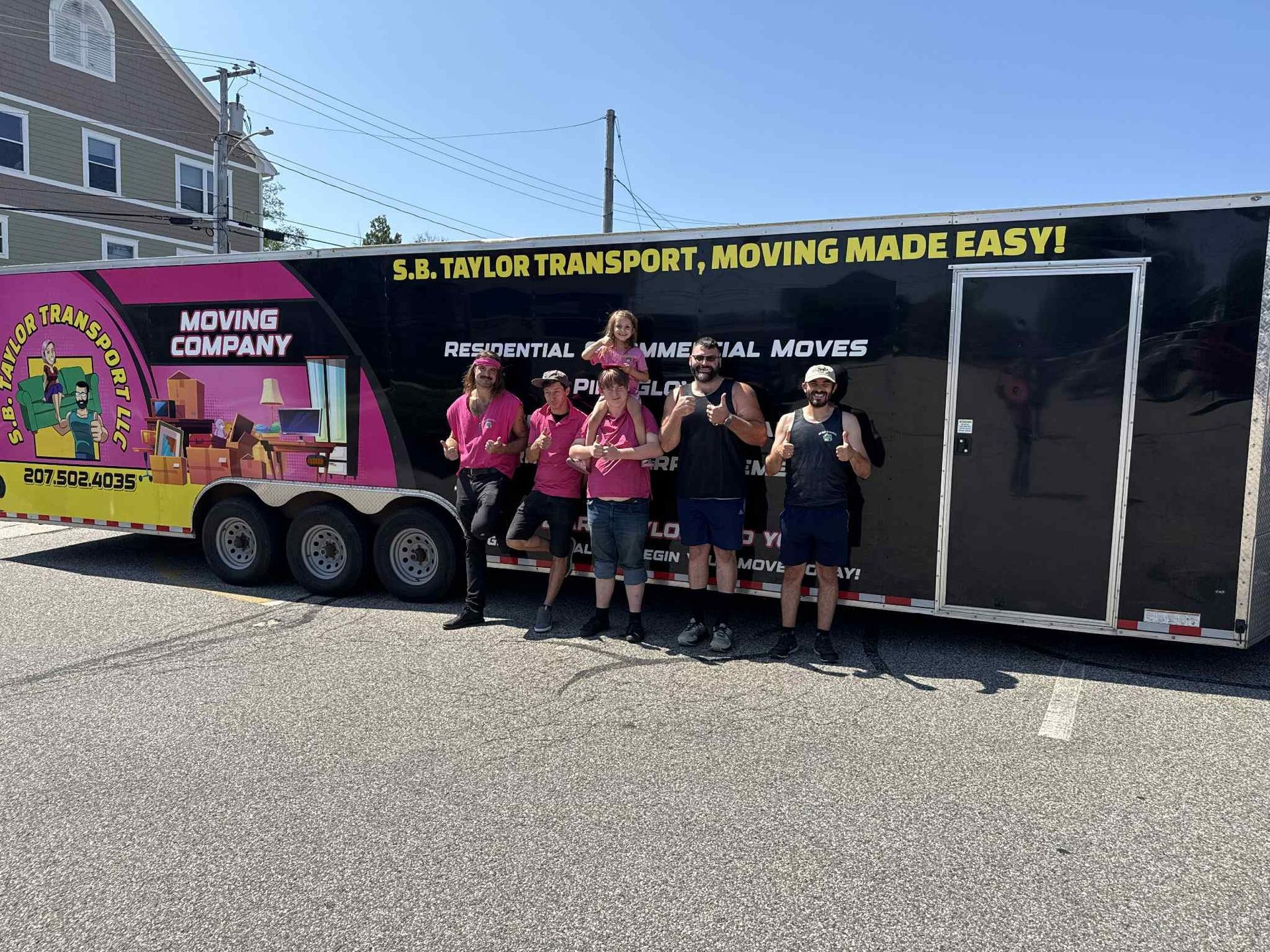 S.B. Taylor Moving team smiling in front of black and pink trailer, ready to help.
