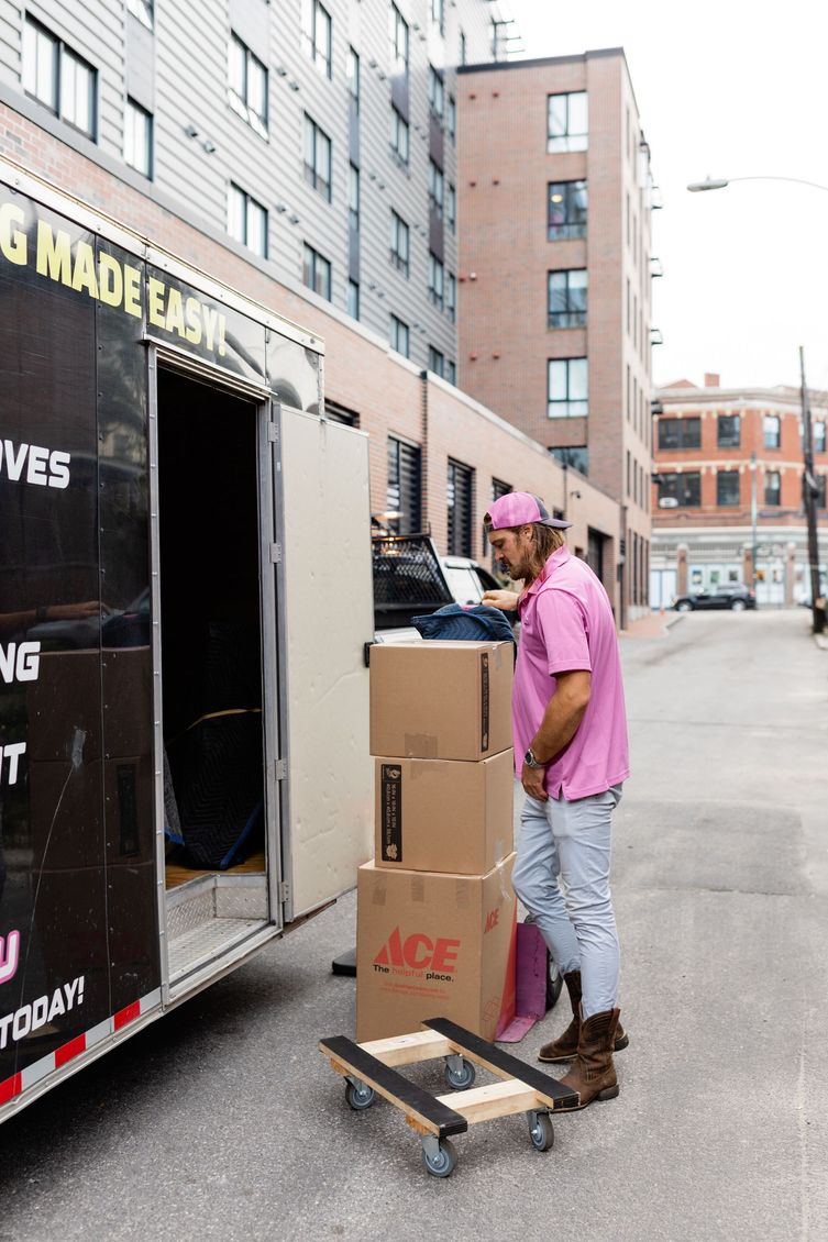 a man and a woman are packing boxes in a kitchen .