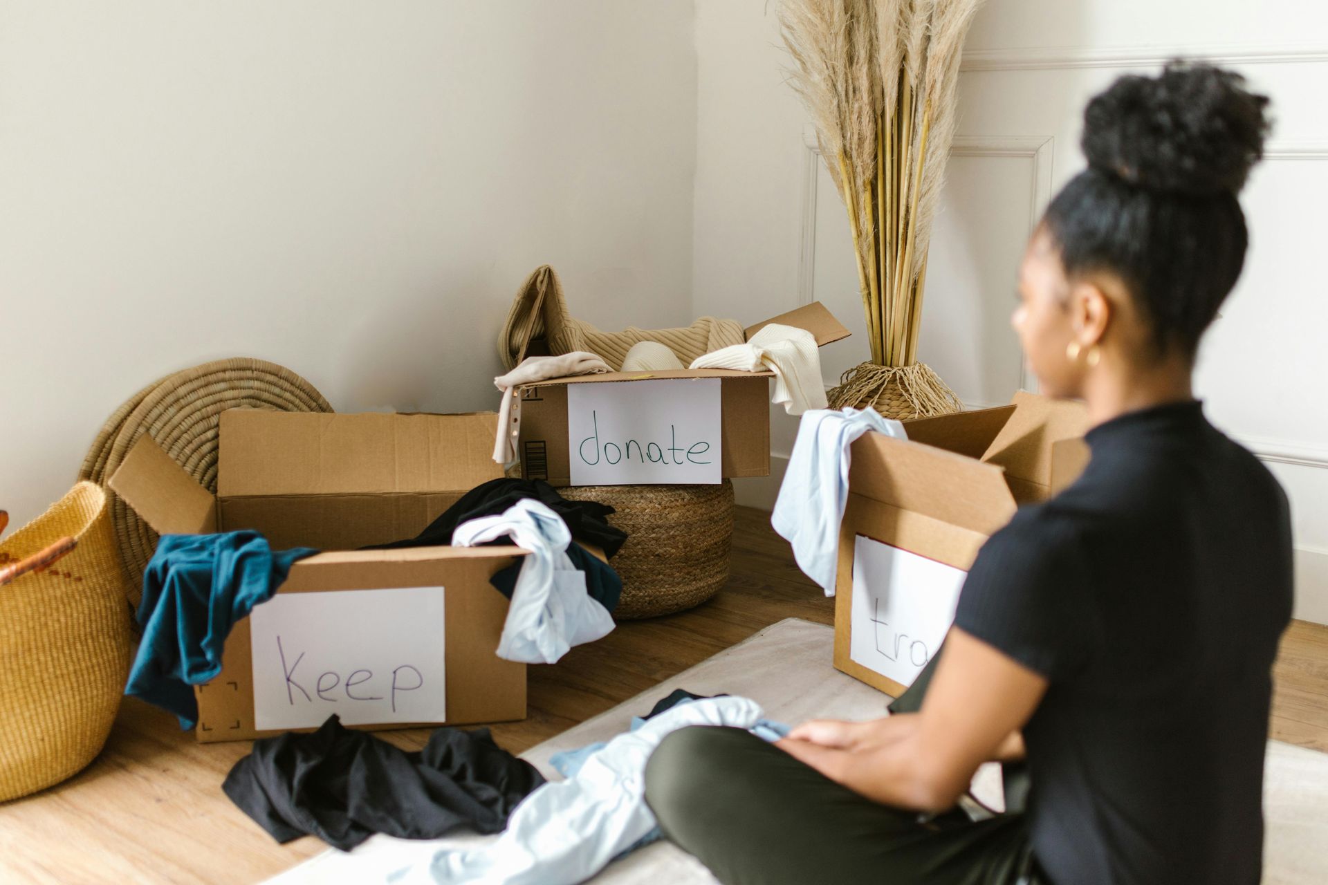 woman sitting sorting clothes into boxes for donation
