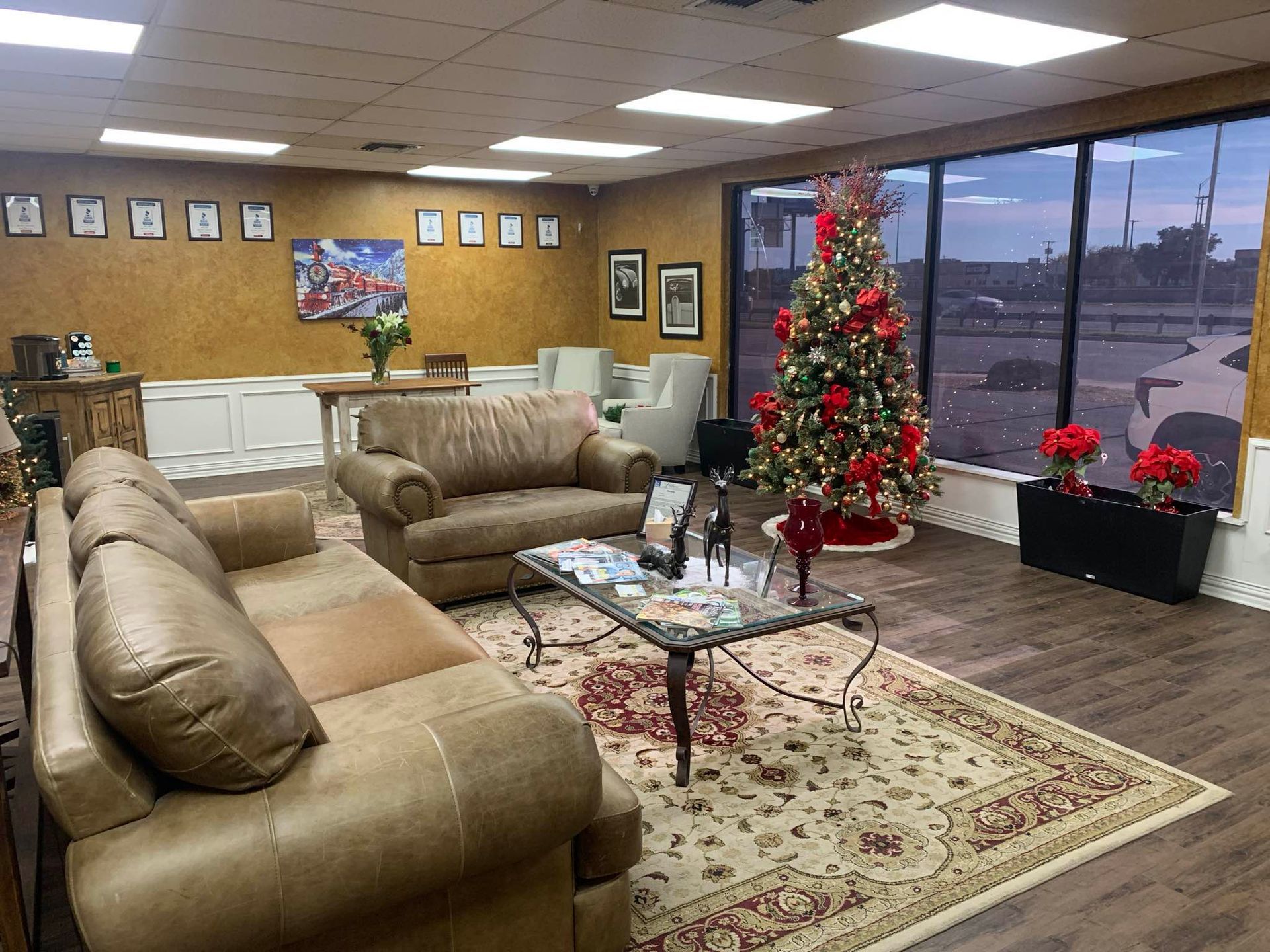 A decorated waiting room with leather furniture, rug, Christmas tree, and large windows.