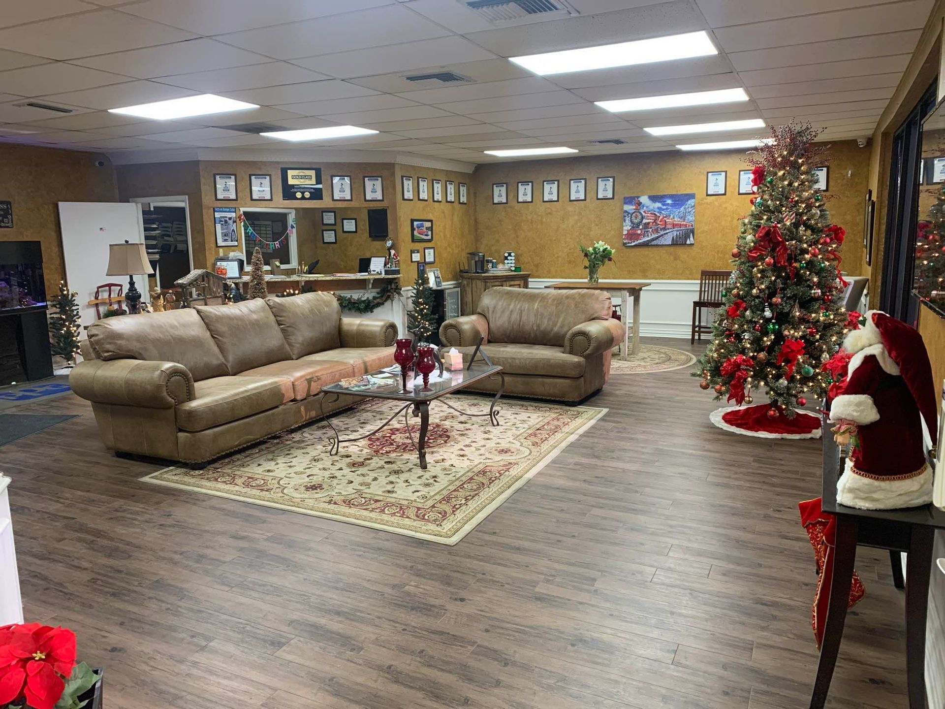 Cozy office space with a brown sofa, chair, Christmas tree, and Santa figure.