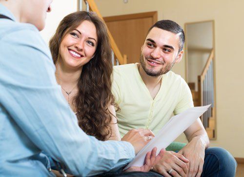 young couple discussing details of private insurance with agent