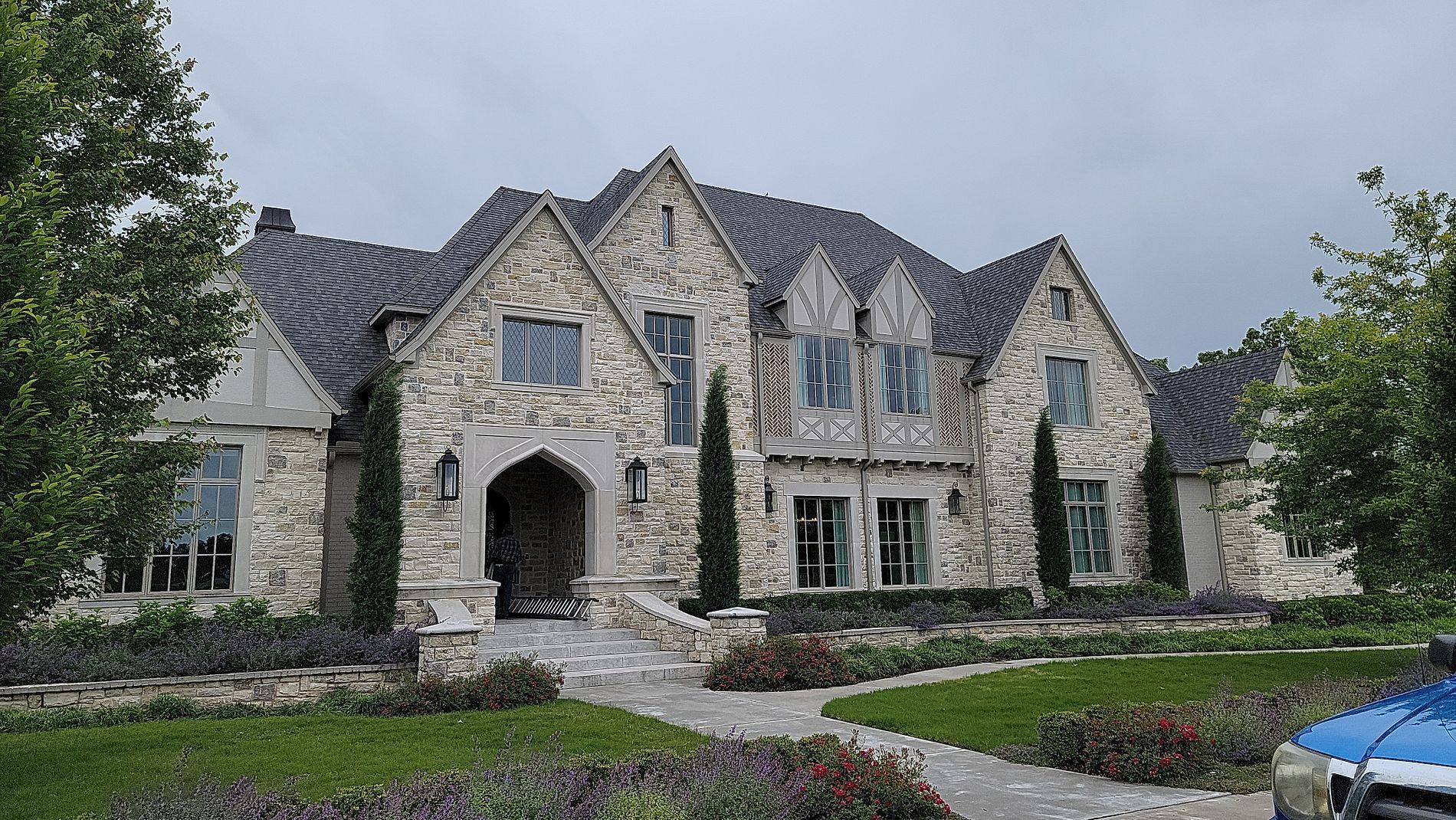 A large stone house with a blue car parked in front of it.