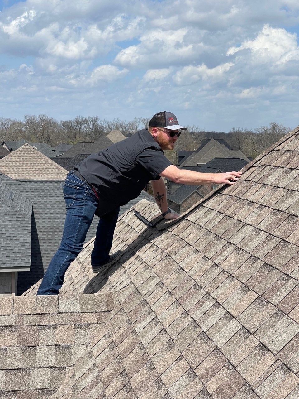 A man is standing on top of a roof working on it.