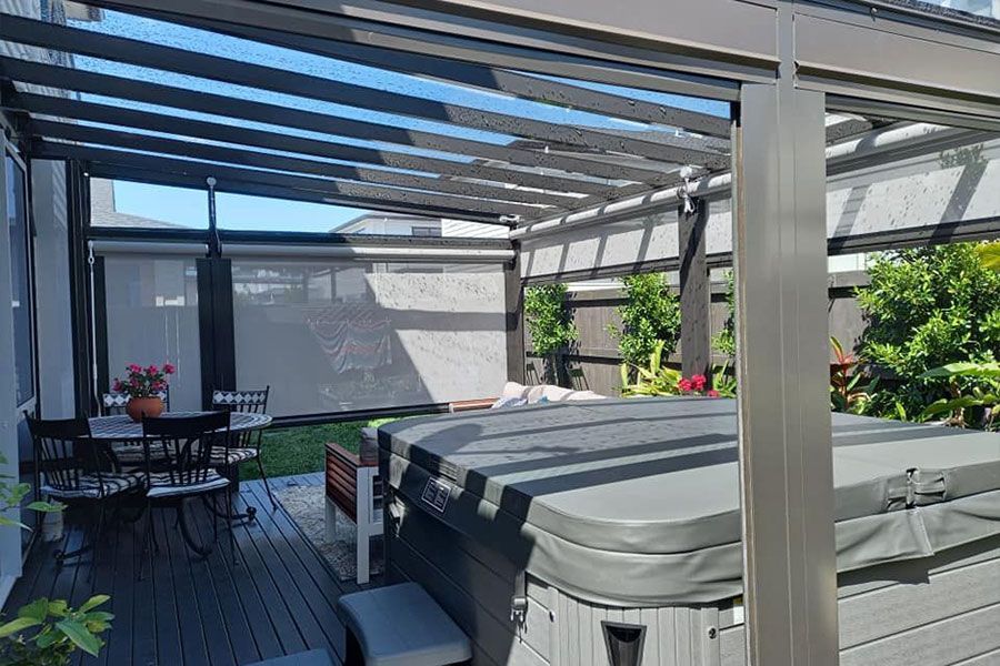 Pergola over hot tub and deck with outdoor dining area, shaded by screens.