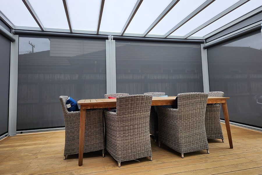 Outdoor dining set under a pergola with gray shades.