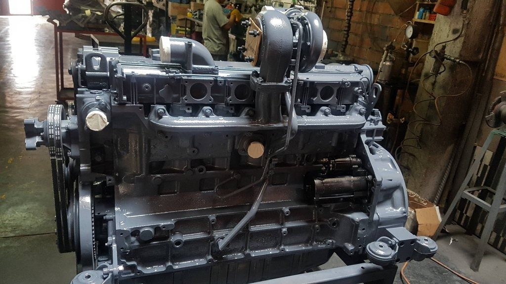 Gran motor industrial negro en un taller, visto de frente entre maquinaria y herramientas.
