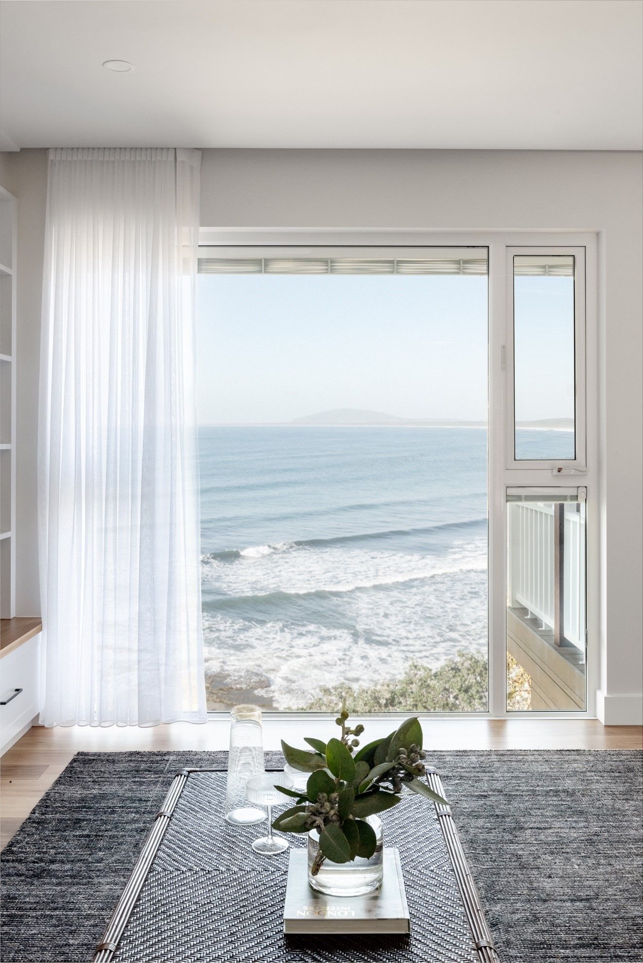 A Living Room With a View of the Ocean Through a Sliding Glass Door — QBC Constructions In Gables, NSW