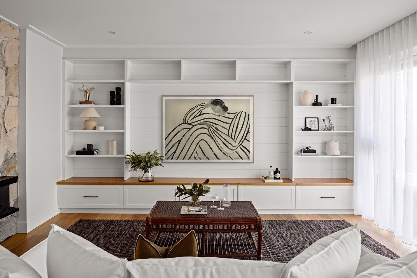 A Living Room With a Couch, Coffee Table, Shelves and a Painting on the Wall — QBC Constructions In Gables, NSW