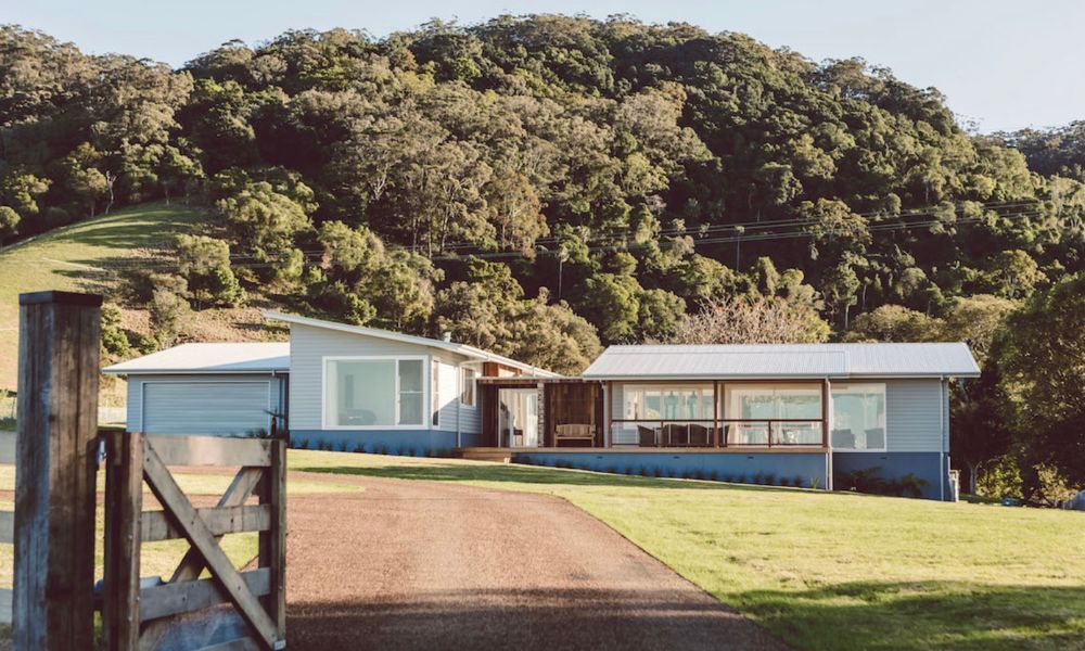 A House is Sitting on Top of a Lush Green Hill Surrounded — QBC Constructions In Willow Vale, NSW