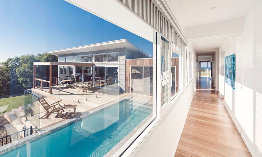 A Long Hallway Leading to a Large House With a Swimming Pool — QBC Constructions In Willow Vale, NSW