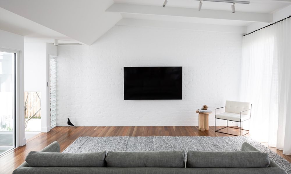 A Living Room With a Couch and a Flat Screen Tv on the Wall — QBC Constructions In Pacific Avenue, QLD