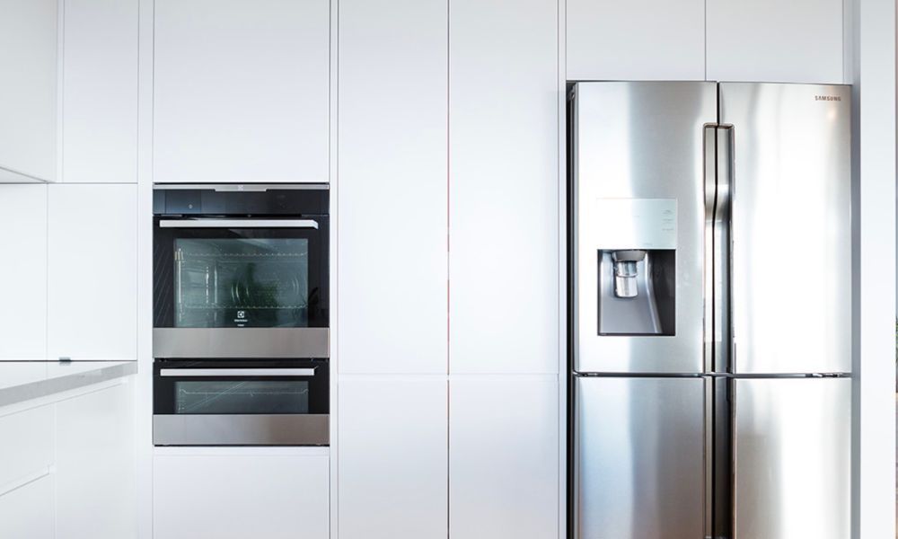 A Kitchen With White Cabinets and a Stainless Steel Refrigerator — QBC Constructions In Gerringong, NSW