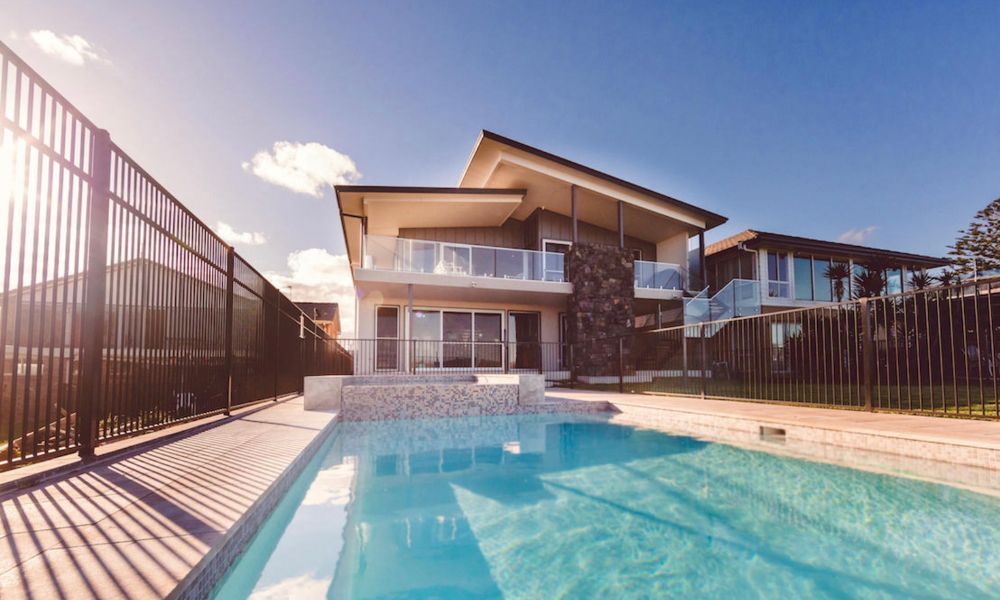 A Large House With a Swimming Pool in Front of It — QBC Constructions In Shellharbour, NSW