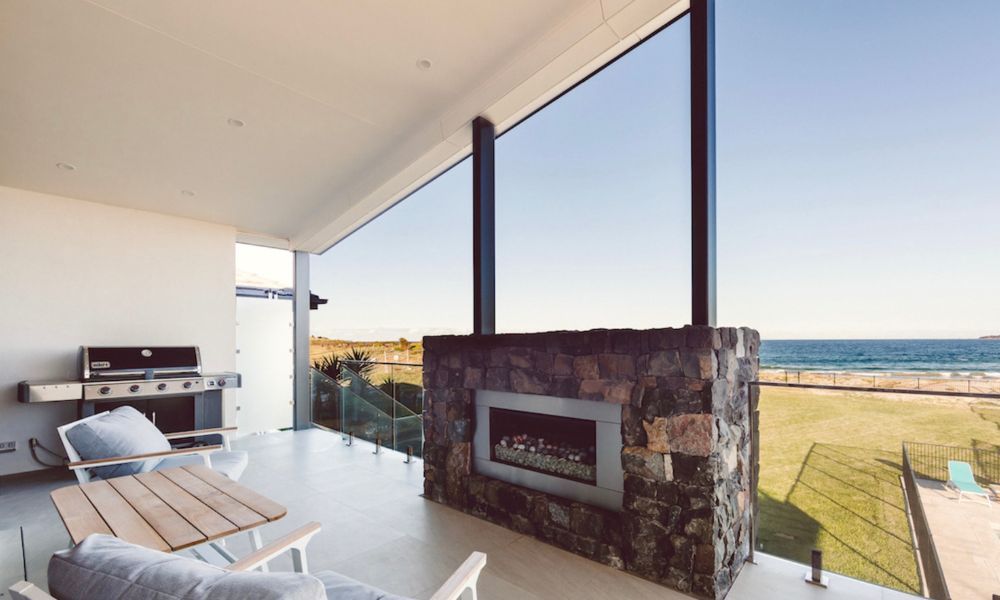 a Balcony With a Fireplace and a View of the Ocean — QBC Constructions In Shellharbour, NSW