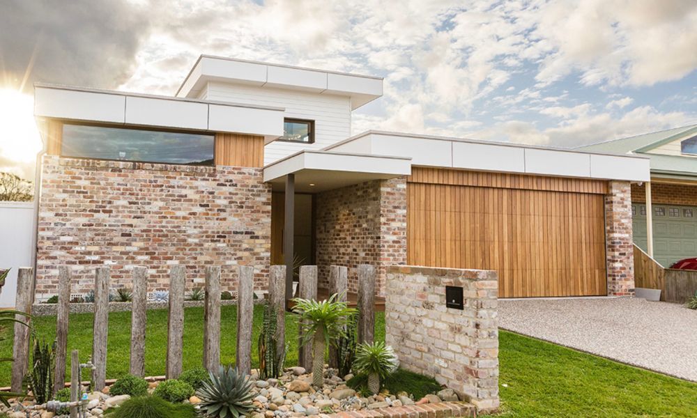 A Modern Brick House With a Wooden Garage Door — QBC Constructions In South Coast, NSW