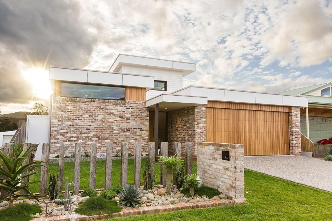 A Modern House With A Wooden Garage Door And A Stone Wall — QBC Constructions In Berry, NSW