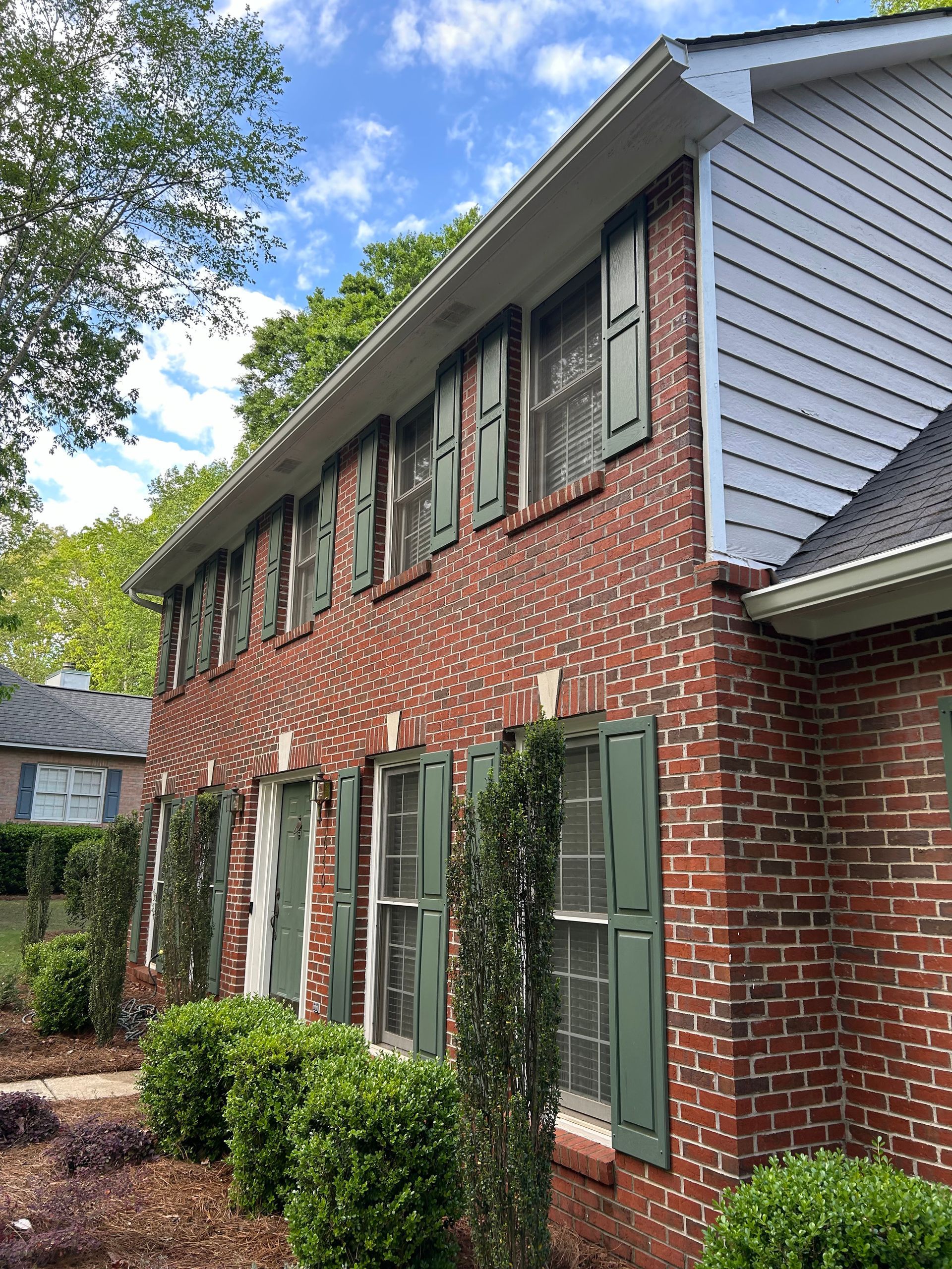 A brick building with green shutters on the windows