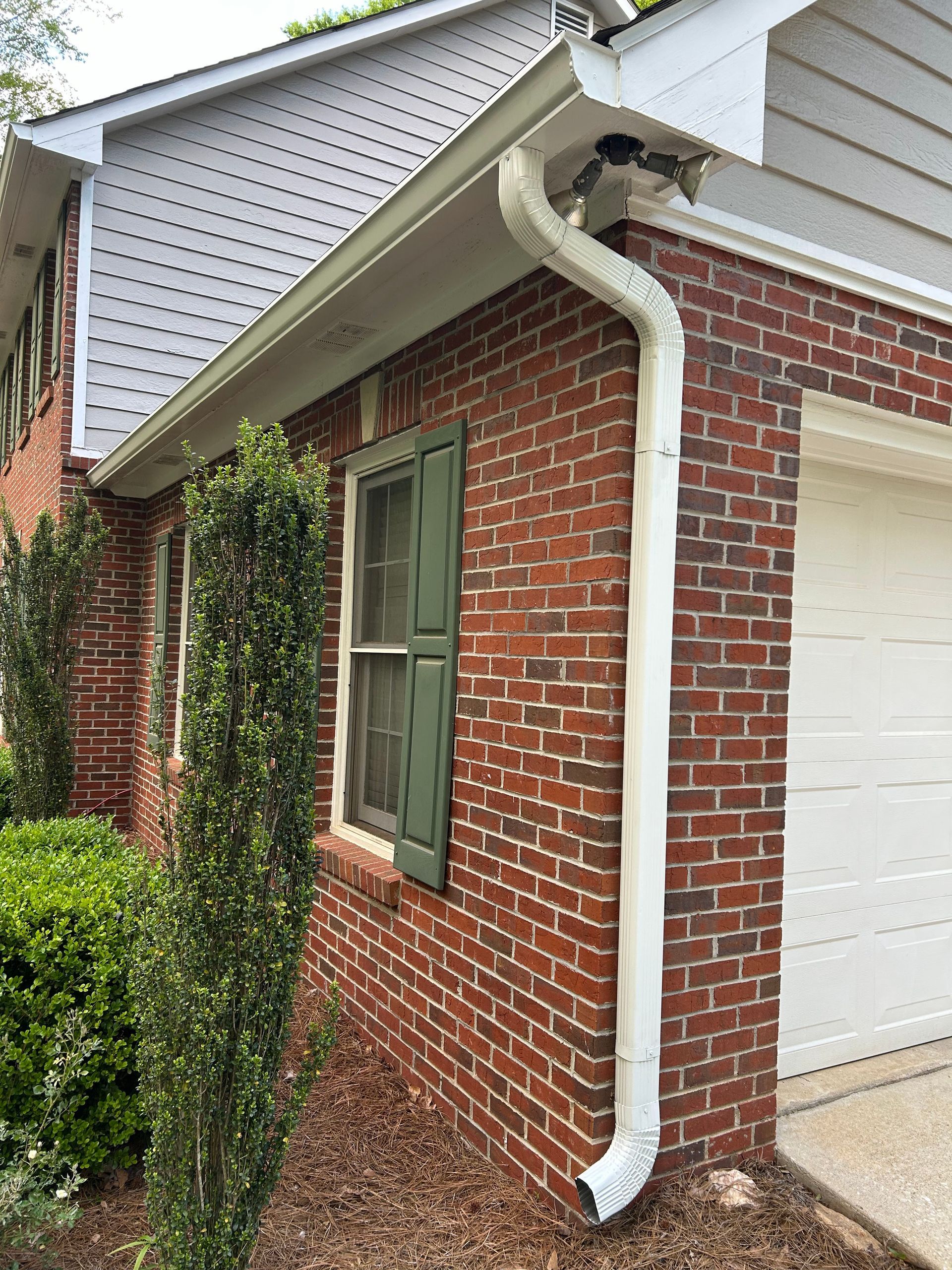 A brick house with a white gutter and a white garage door.