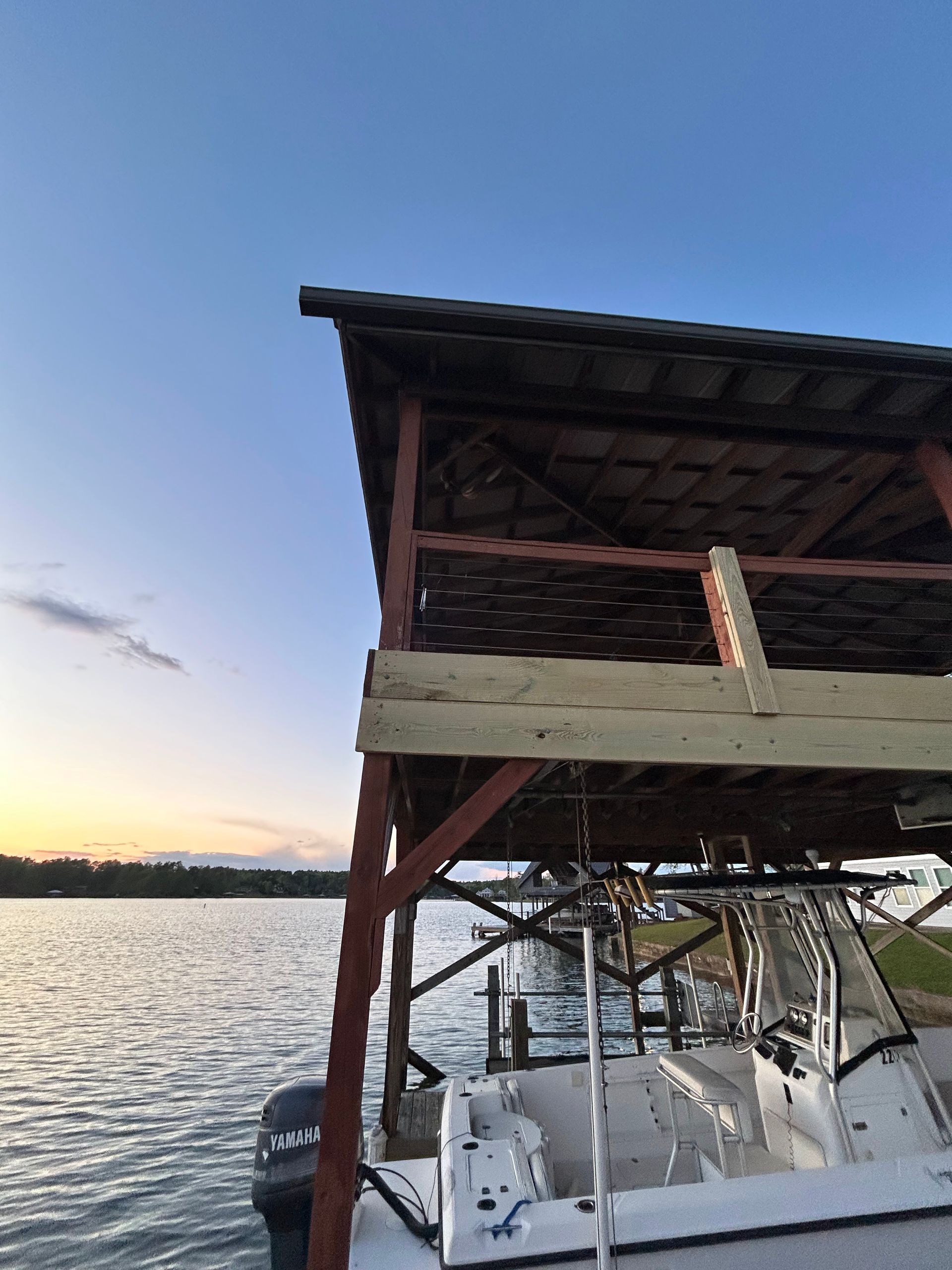 A boat is docked under a wooden structure in the water.