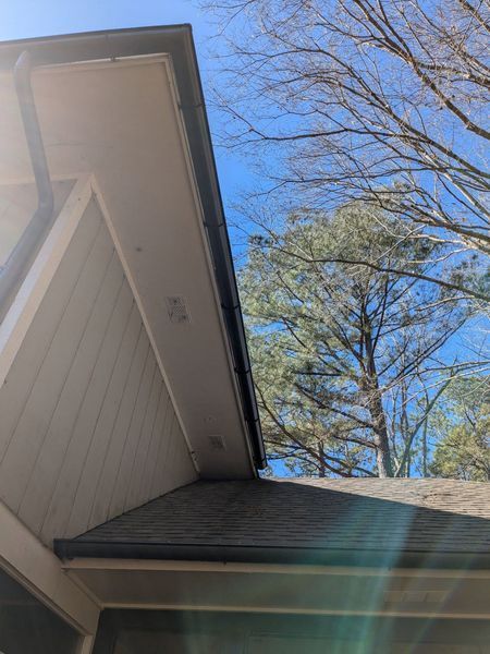 Looking up at the roof of a house with trees in the background.
