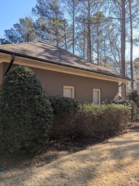 A house with a roof that is surrounded by trees and bushes.