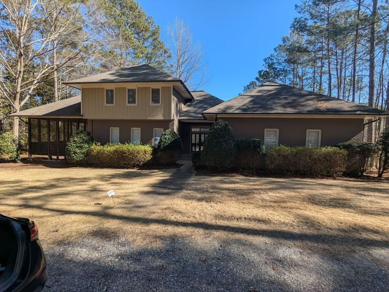 A large house with a car parked in front of it surrounded by trees.