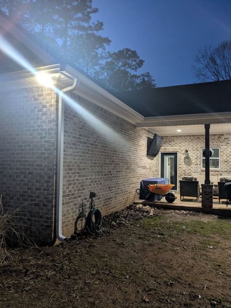 A brick house with a porch and a light on the side of it at night.