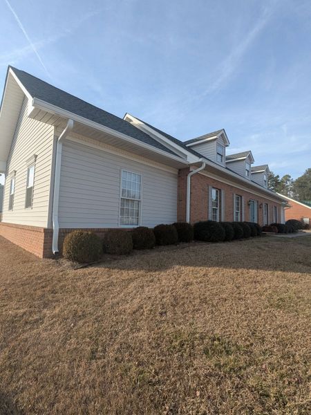 A large house with a lot of windows is sitting on top of a lush green field.
