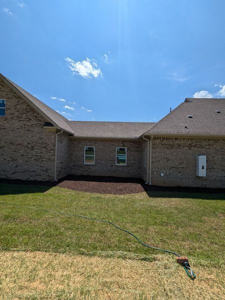 A large brick house with a large lawn in front of it.