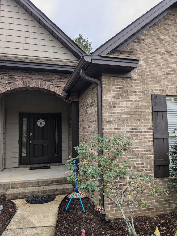 A Brick House With a Black Door and a Black Gutter