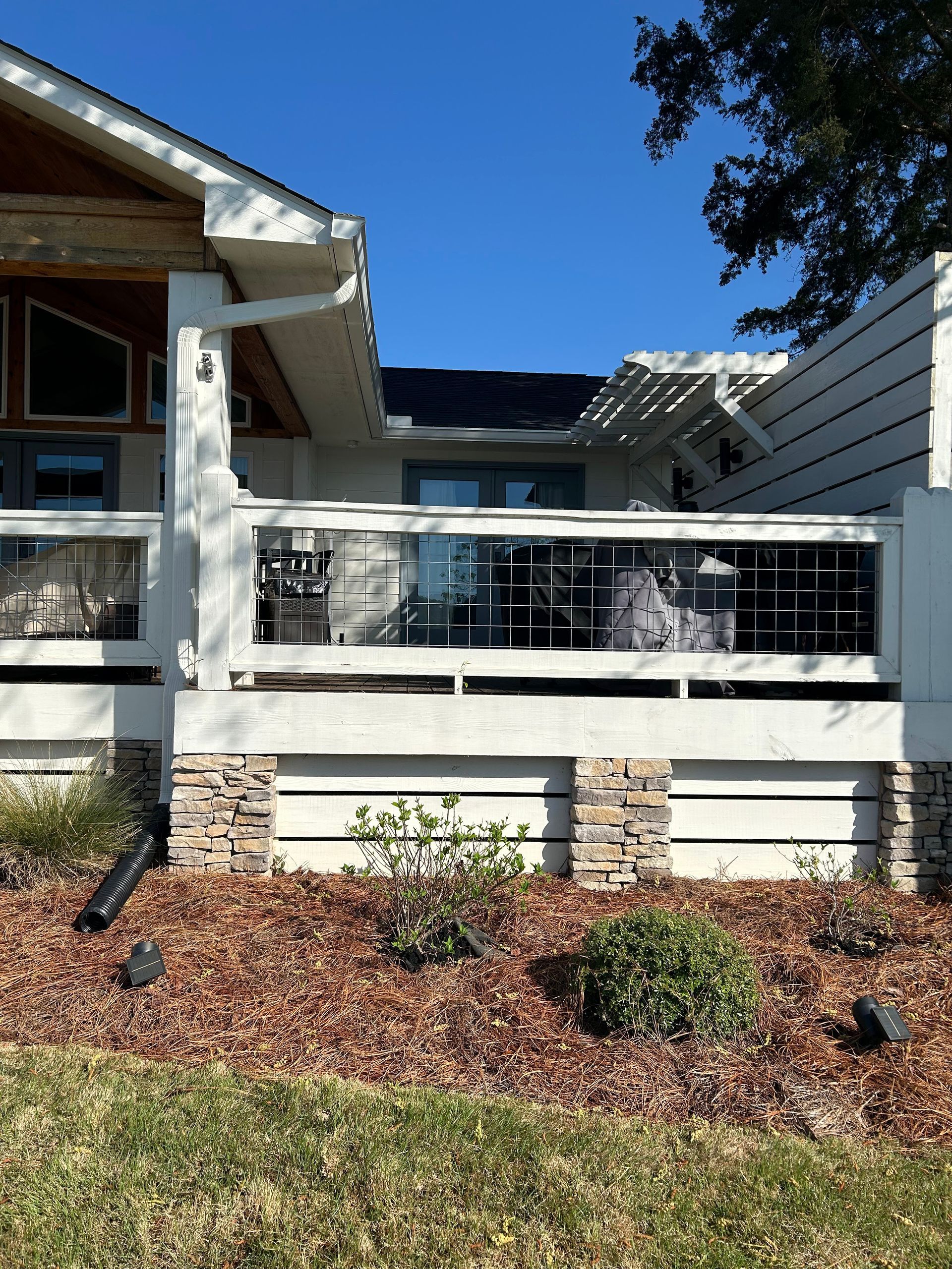 A house with a large deck and a blue sky in the background