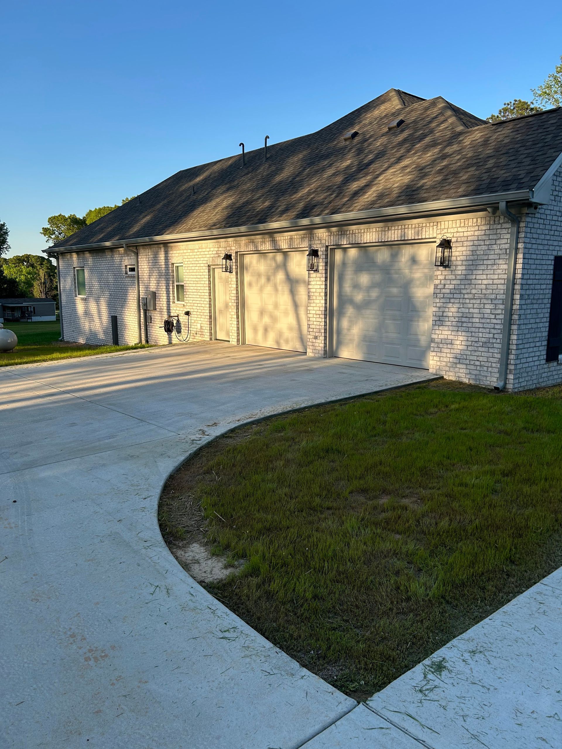 A white brick house with a driveway leading to it