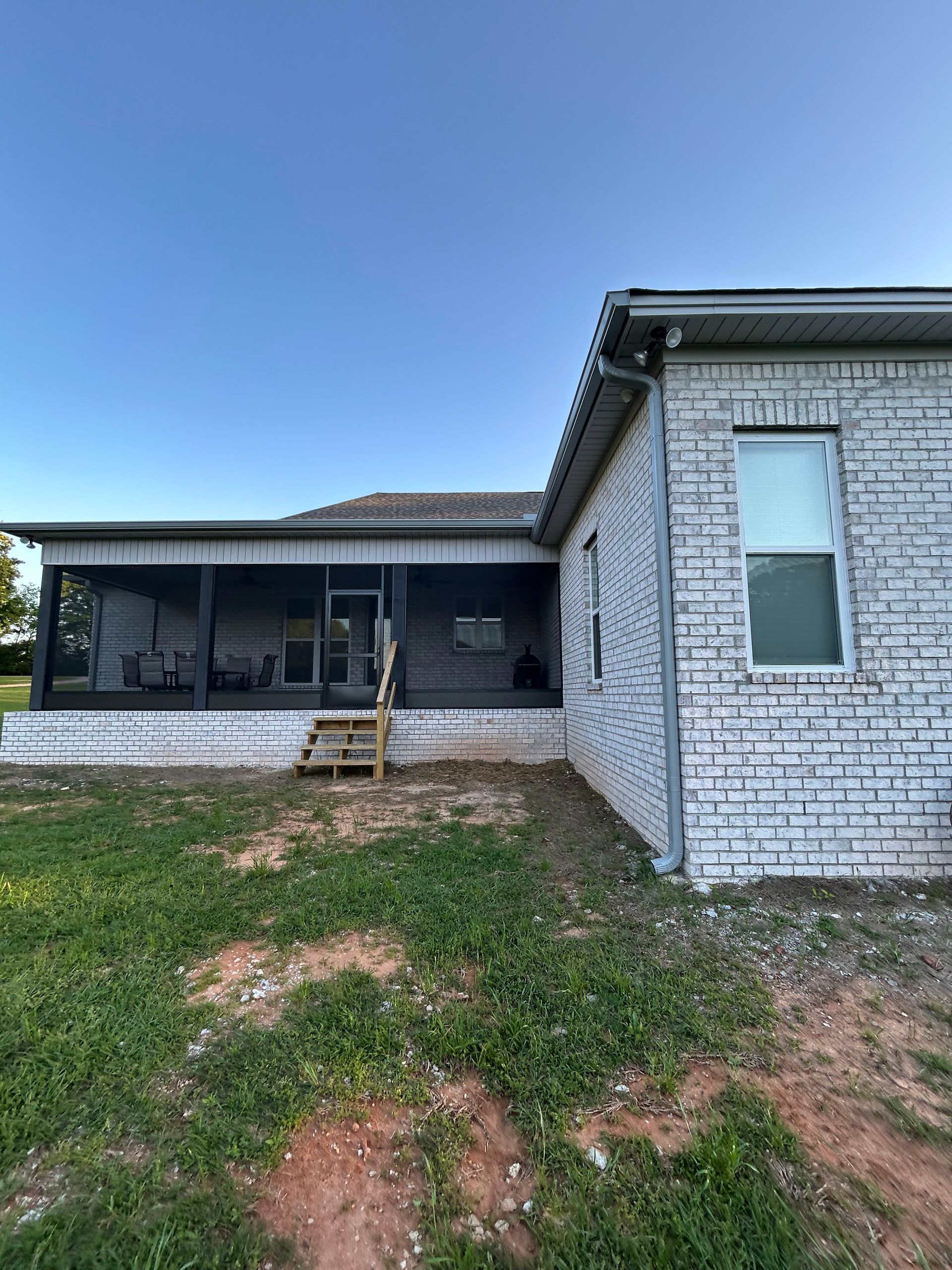 A white brick house with a porch and stairs