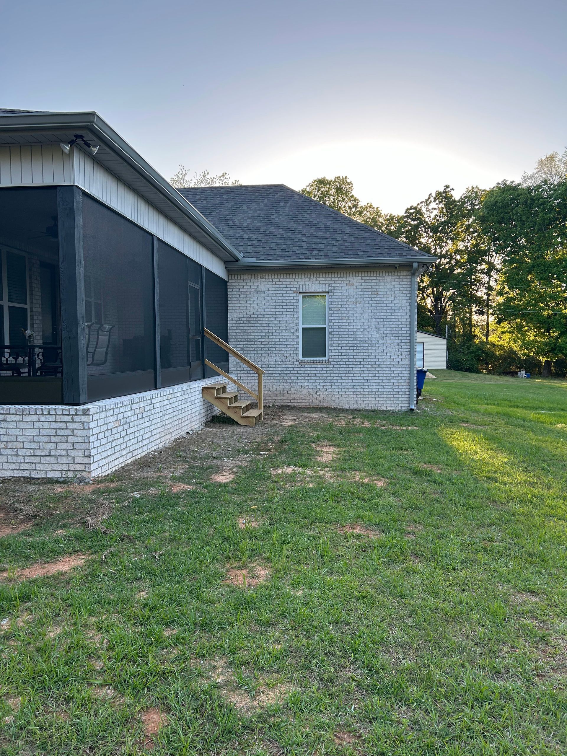 The back of a house with a screened in porch and stairs.