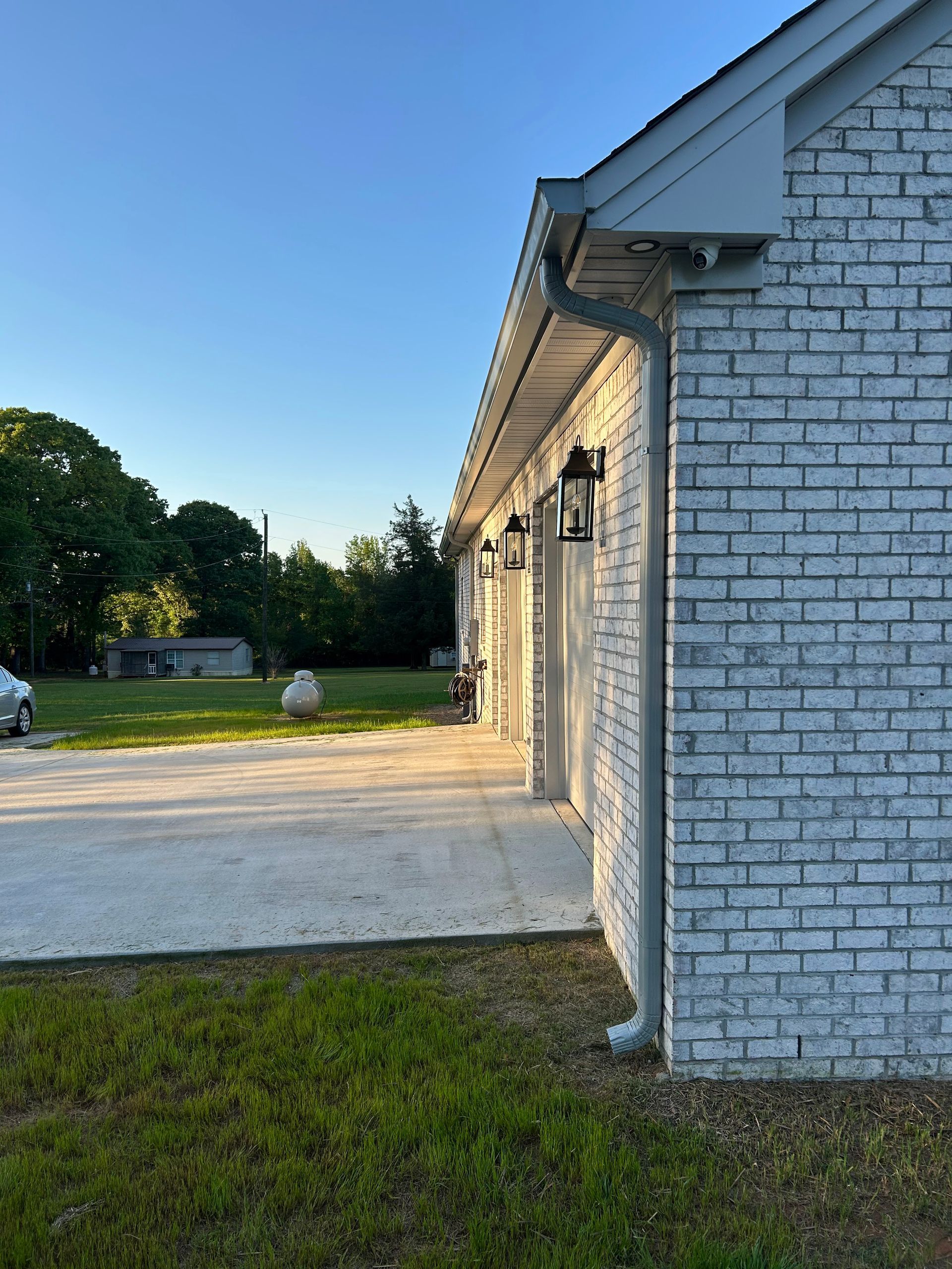 A white brick house with a driveway in front of it.