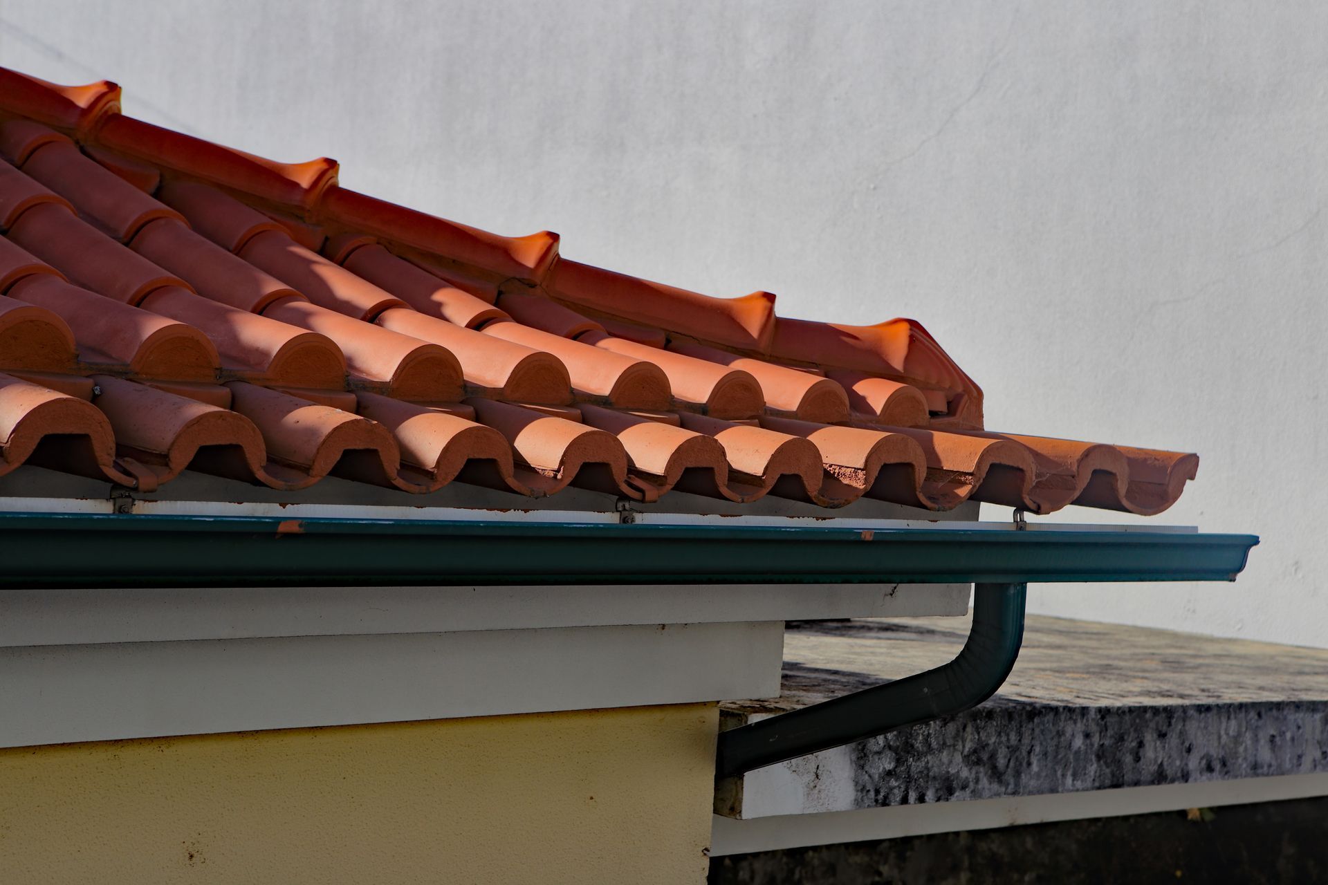 A Roof With Red Tiles and a Green Gutter