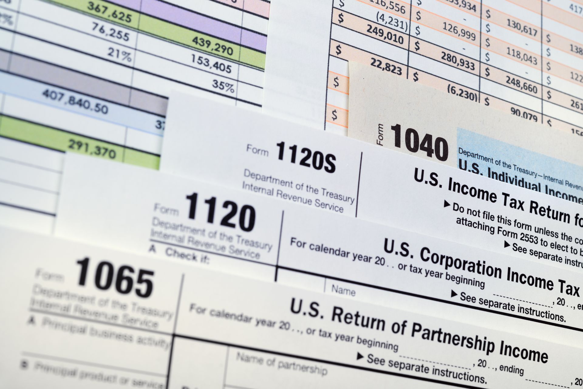 Tax forms, US currency, and a pen on a light blue background.