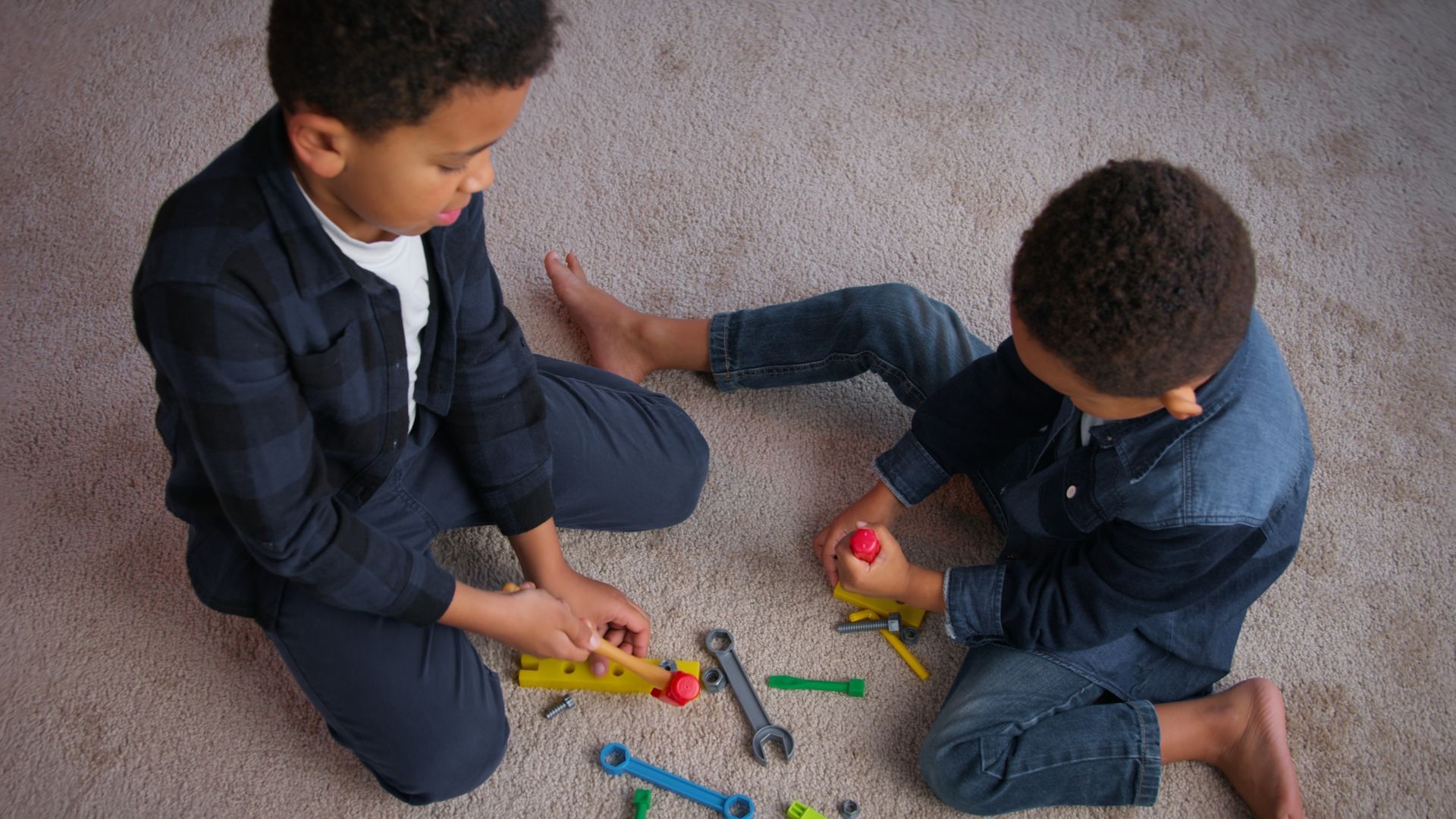 Family of four smiles while lying on a light-colored carpet with their feet up.