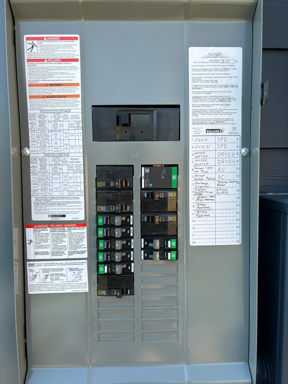 Electrical circuit breaker panel with several green and black switches in a metal cabinet.