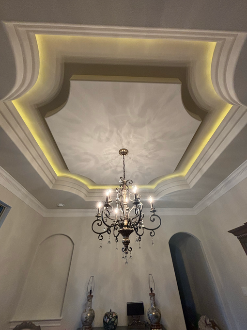 Person installing a track lighting fixture on a textured off-white ceiling; hands adjusting the light head.