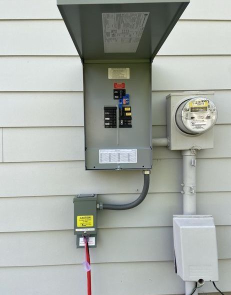 Exterior electrical panel on a white-sided house with a meter and an outlet.