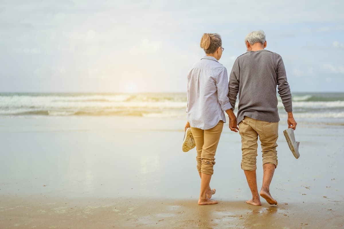 a man and woman walking on the beach holding hands